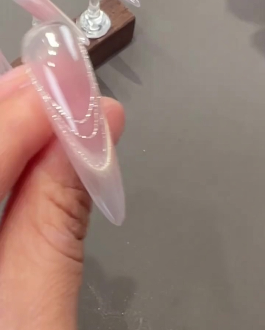 Une pince à épiler appliquant de petites fleurs séchées délicates et de minuscules breloques perles sur un ongle.
