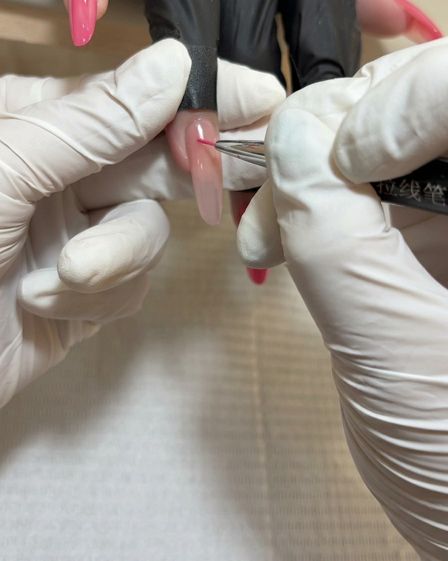 Gros plan dun pinceau liner appliquant du gel rouge profond au centre du troisième groupe de pétales.
