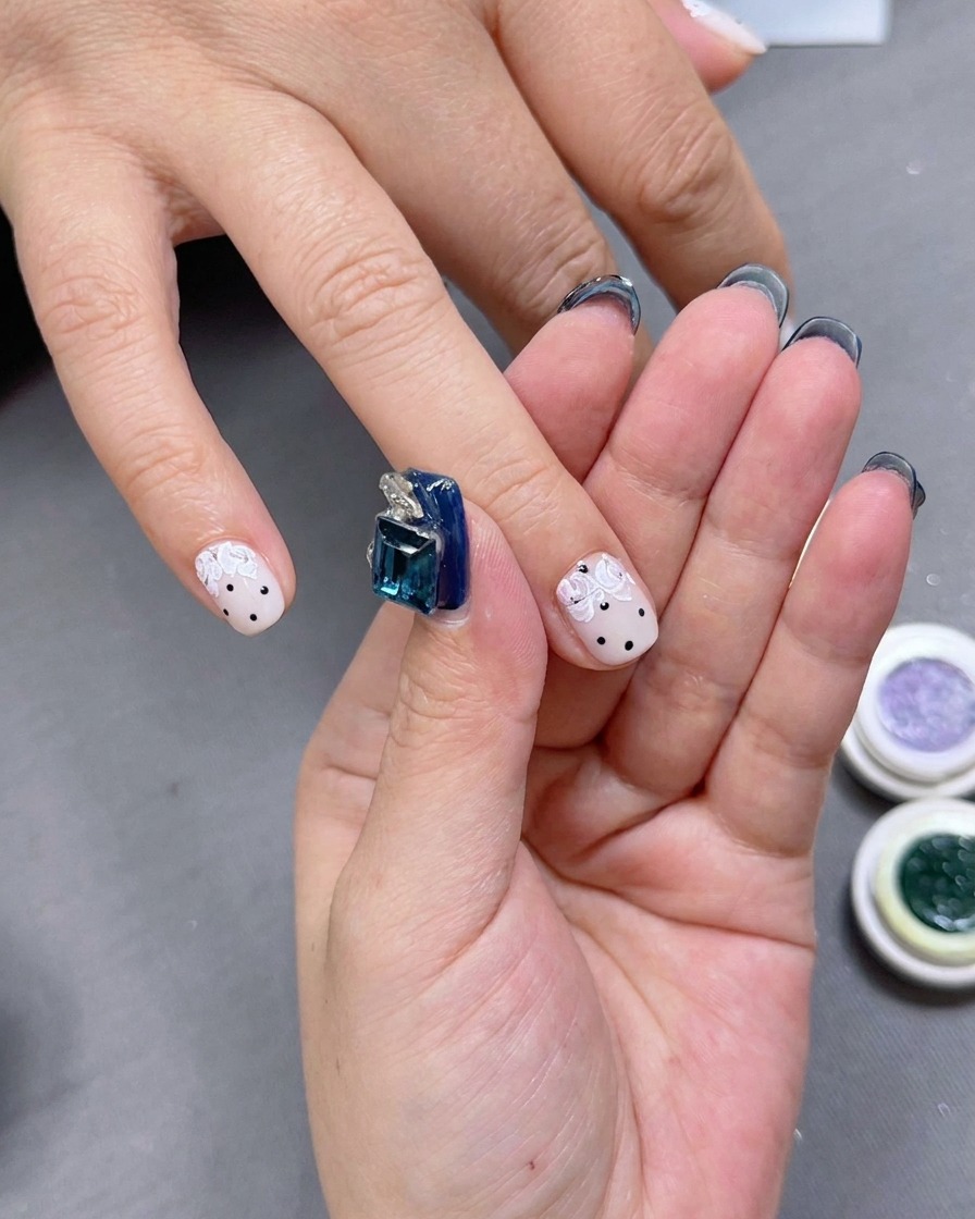 Une styliste ongulaire appliquant de petites touches de gel vert autour des pétales de rose.