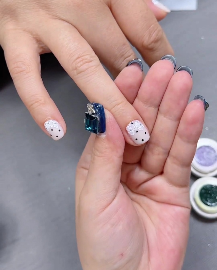 Gros plan sur un ongle montrant le nail art floral raffiné avec des espaces négatifs.