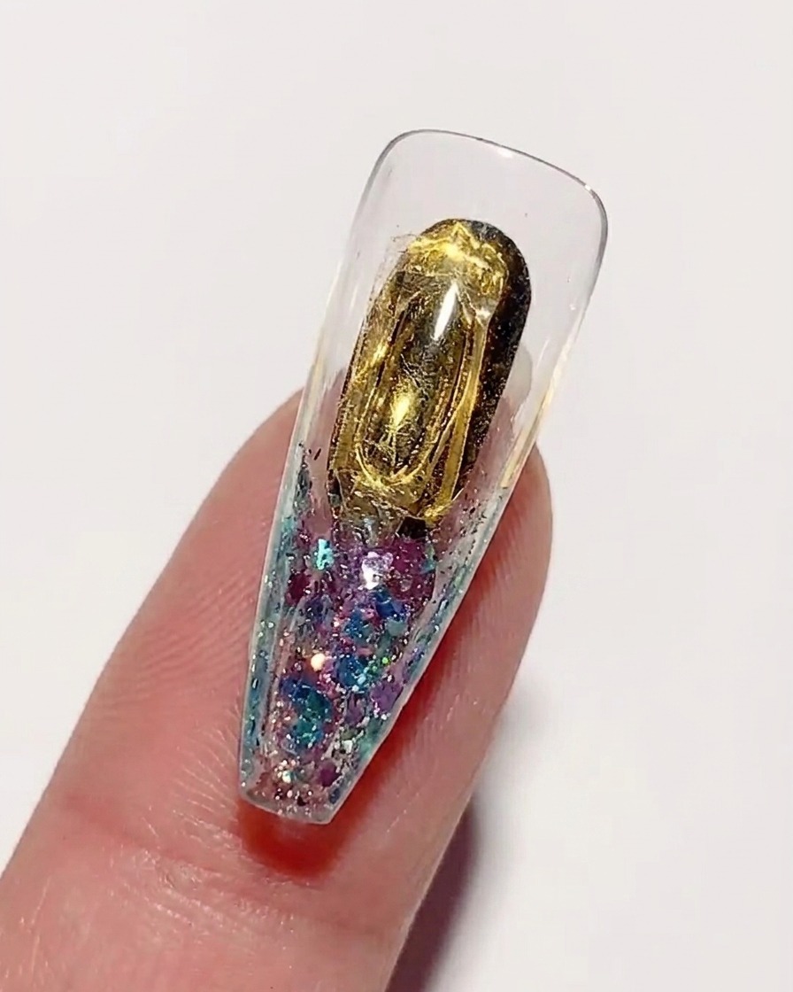 Application dune colle à ongles dure, épaisse et transparente, sur la surface interne dorée dune capsule.