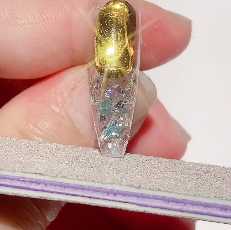 Une lime à ongles affinant les bords dune capsule texturée pour assurer un périmètre lisse.