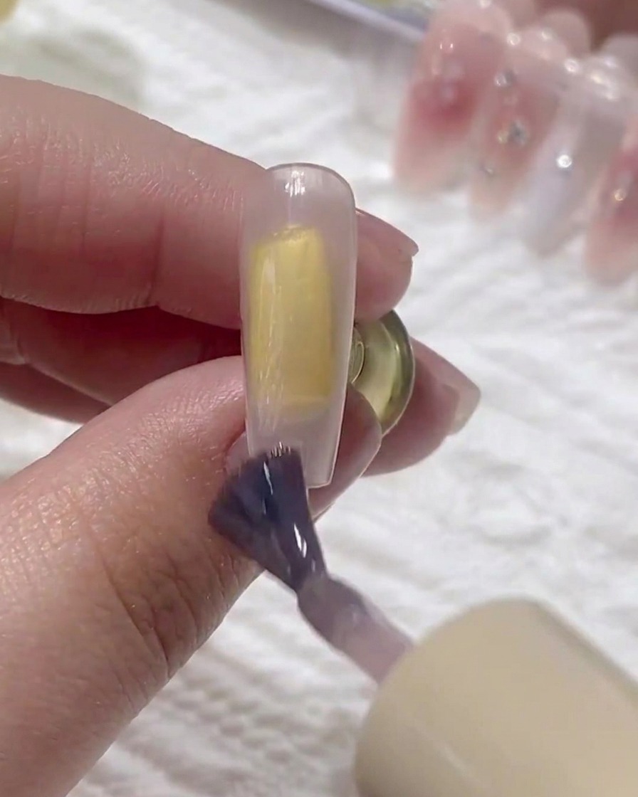 Un pinceau appliquant une deuxième couche de gel de base sur longle.