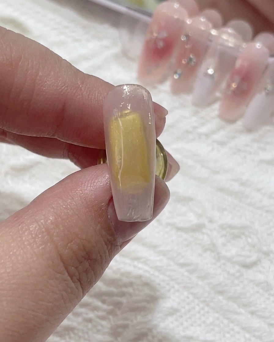 Un pinceau appliquant du blooming gel transparent sur la surface de longle.