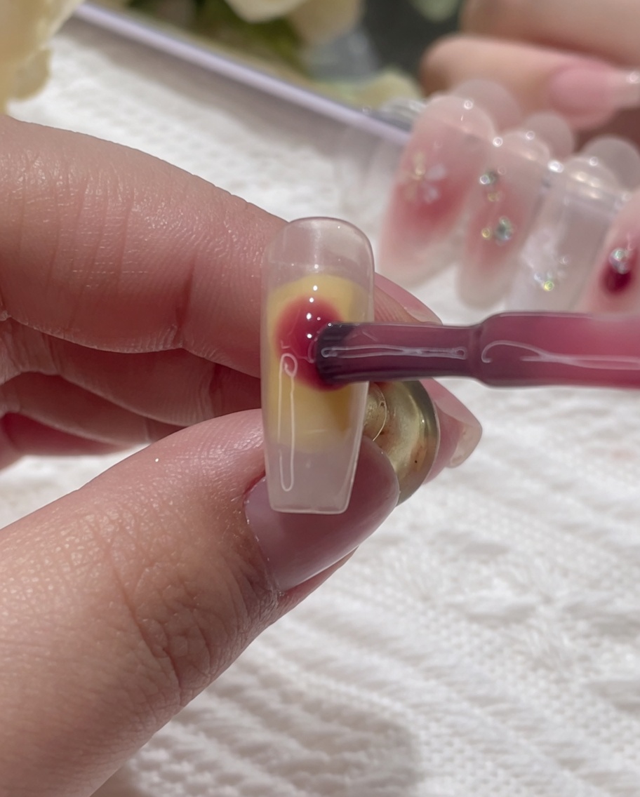 Du gel rose déposé en points sur la surface humide de longle.