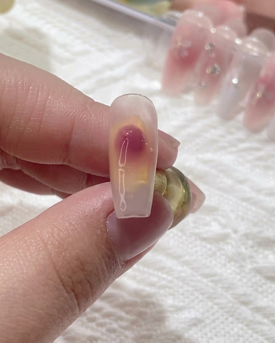 Gros plan sur un pinceau créant un dégradé blush sur un ongle.