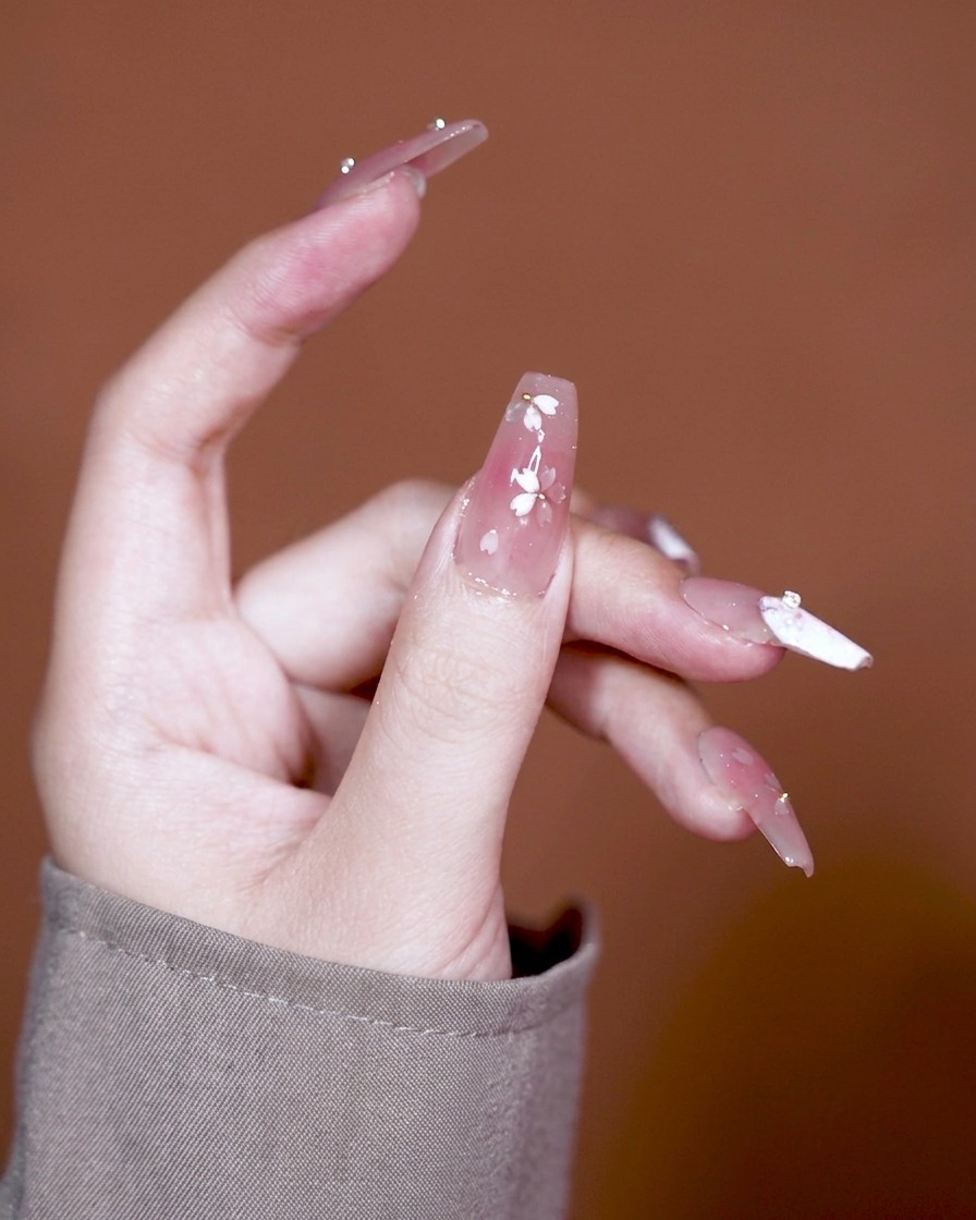 Un pinceau appliquant un gel adhésif épais sur une base dégradée rose.