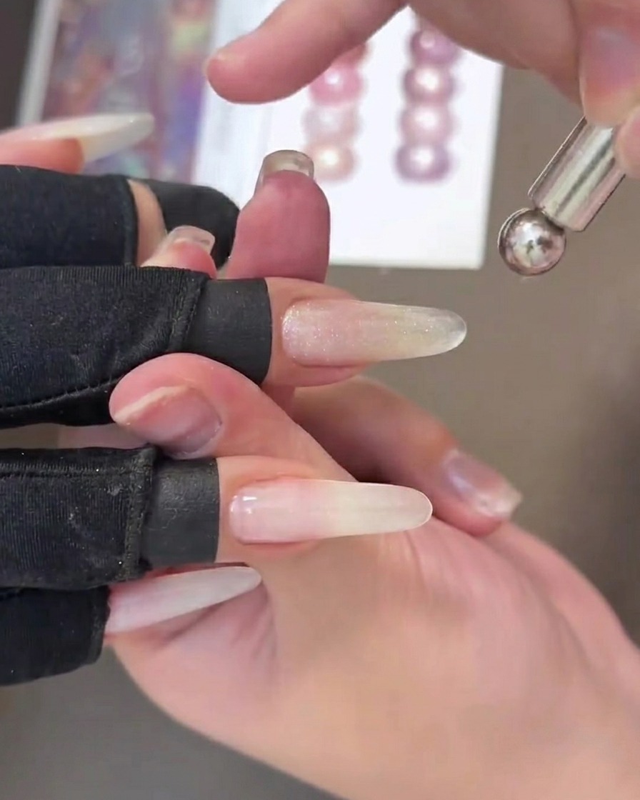 Une vue rapprochée dun ongle avec du gel œil de chat humide, montrant une traînée métallique tirée sur le centre par un outil magnétique portatif.
