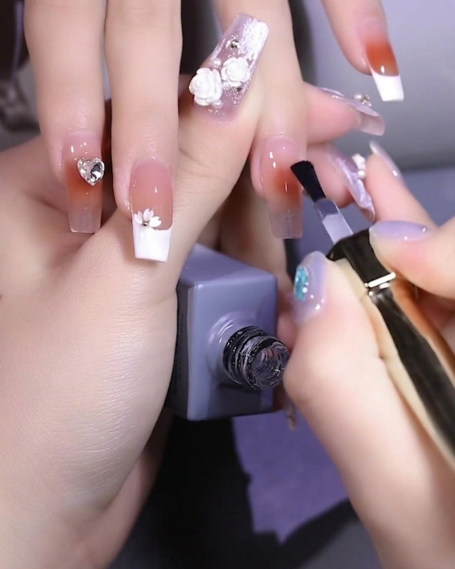 Un pinceau à ongles appliquant un gel de base transparent renforçateur sur un ongle naturel.