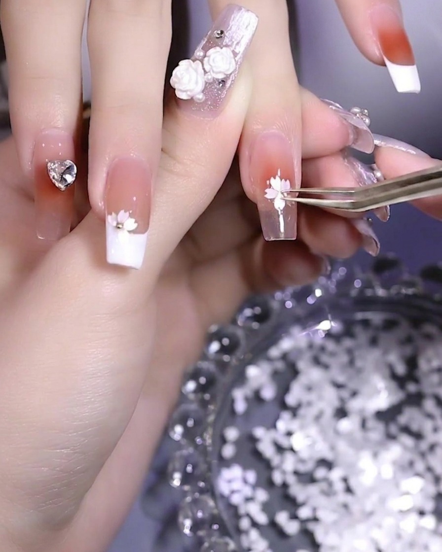 Une petite bille métallique en train dêtre placée au centre dun design de fleur de cerisier en paillettes.