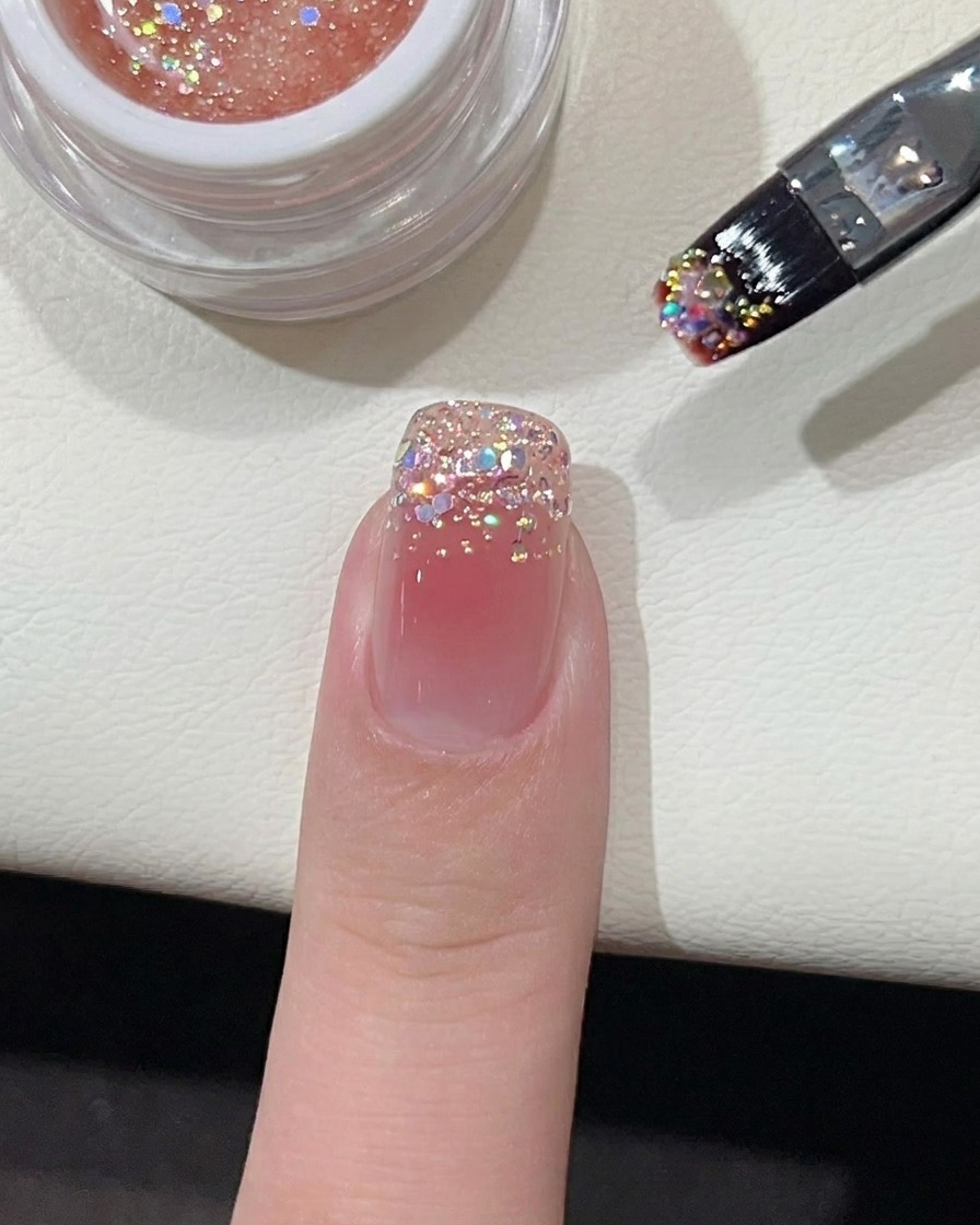 Un petit point de vernis gel rose vibrant placé au milieu dun ongle recouvert de base nude.