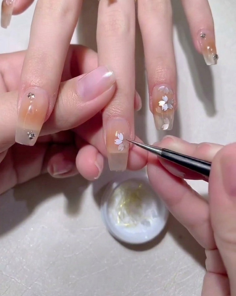 Une pince déposant un sequin sakura sur la surface humide.
