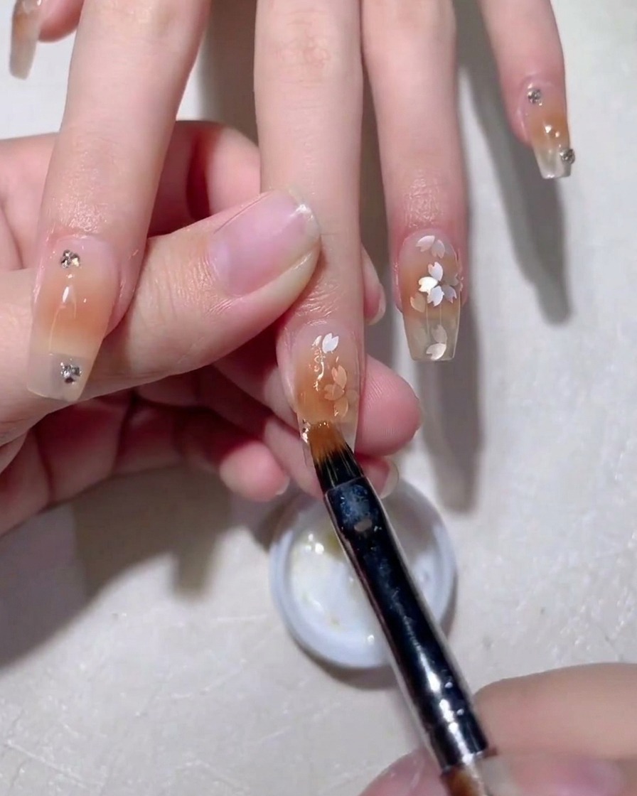 Un pinceau lissant le gel de construction sur les sequins.