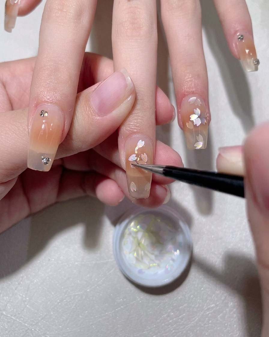 Un pinceau appliquant une base en gel blanc laiteux sur un ongle naturel.