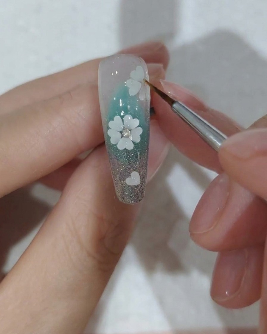 Gros plan des cristaux posés sous une lampe à ongles professionnelle.