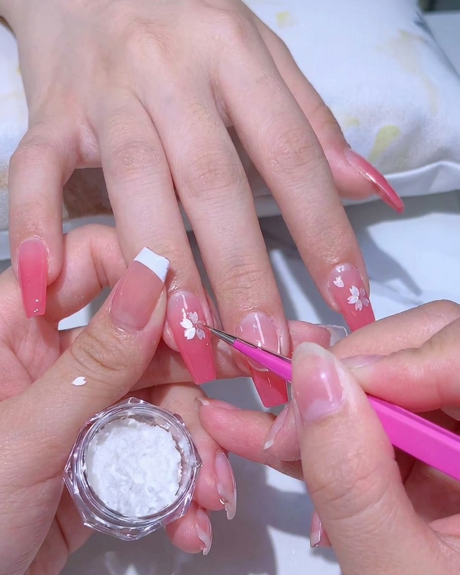Application dun gel adhésif transparent sur une manucure en dégradé rose avec un pinceau fin.