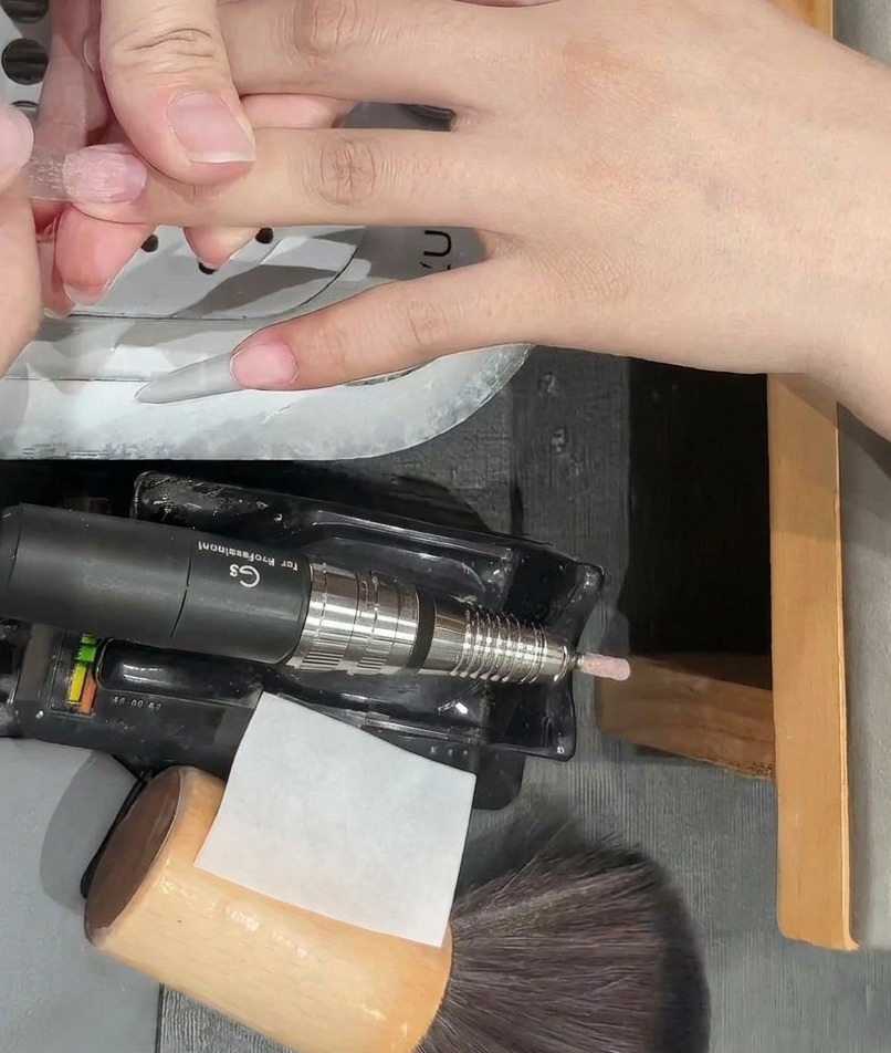 Gros plan sur une capsule dongle transparente posée sur un ongle naturel.