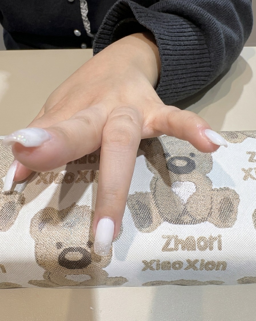 Main sous une lampe UV en train de catalyser les ongles avec le dégradé blanc.