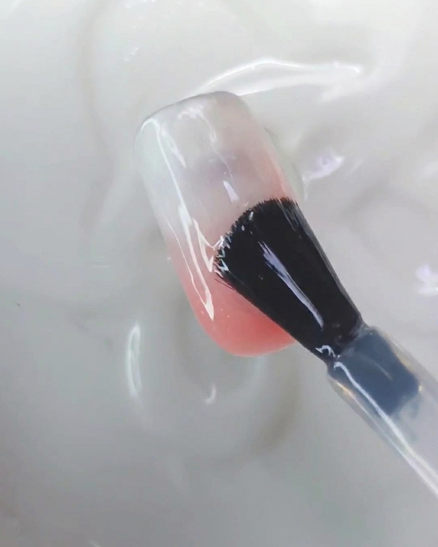 Un outil en silicone frottant de la poudre chrome aurora sur la surface dun ongle.