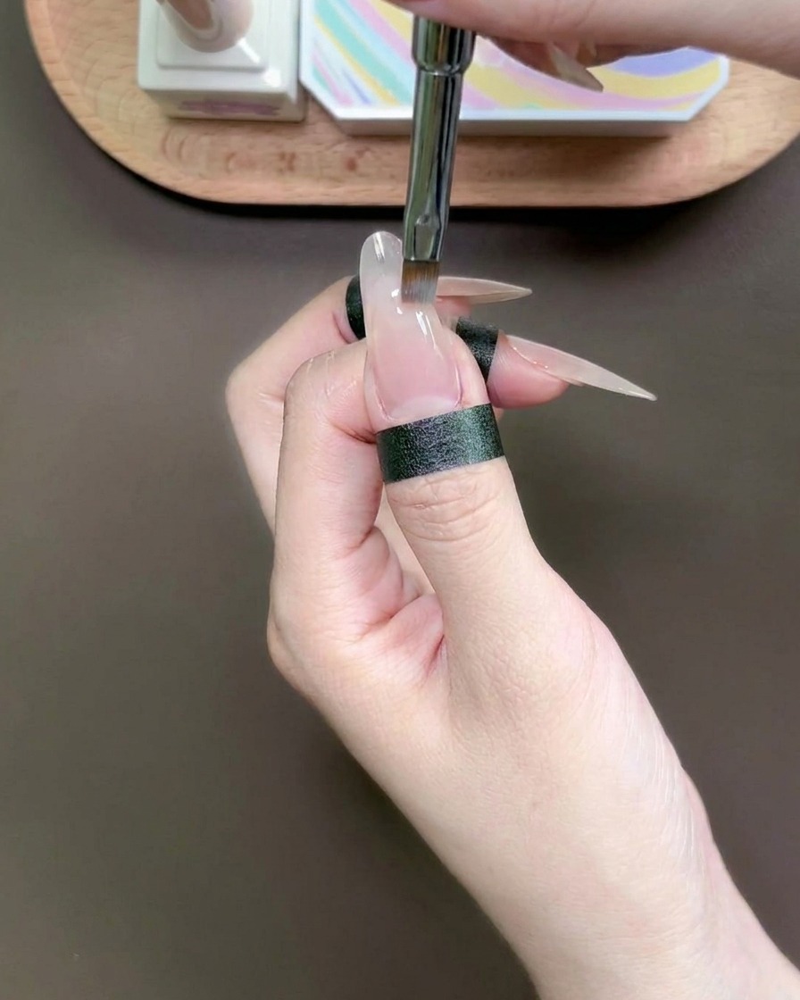 Un outil de précision déposant une goutte de gel bleu sur le bout dun ongle.