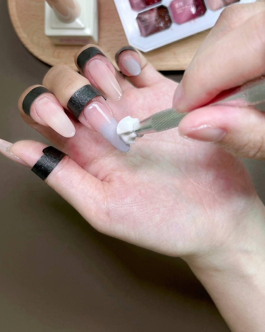 Une éponge estompant du gel bleu sur un ongle pour créer un effet ombré.
