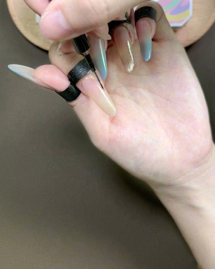 Un pinceau liner tirant délicatement le gel œil-de-chat sur lindex pour créer un dégradé lisse.