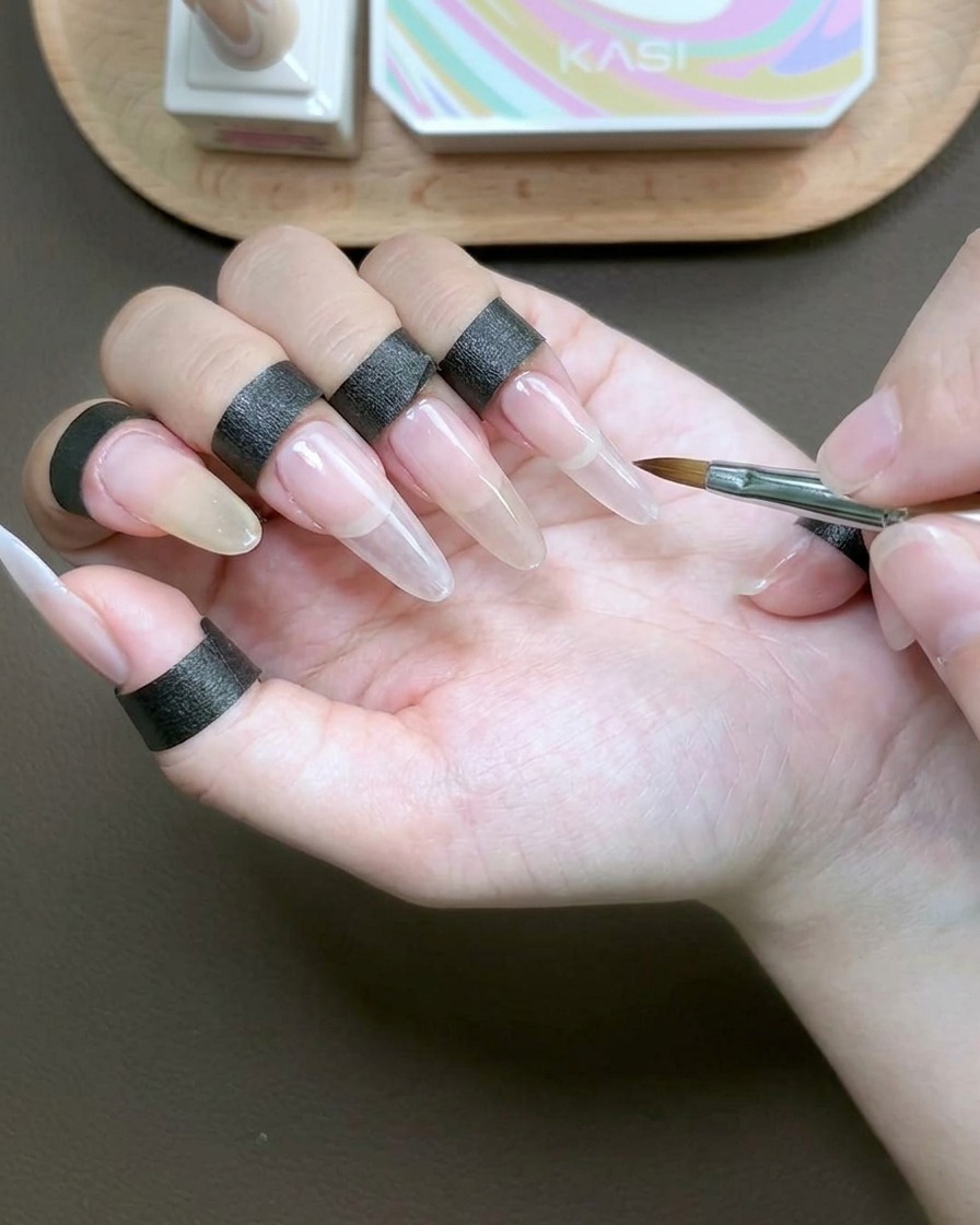 Un pinceau appliquant un gel de construction transparent visqueux sur toute la surface de longle pour encapsuler.