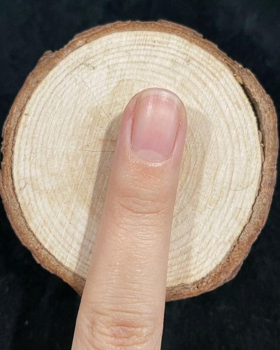 Un pinceau à ongles estompant légèrement la jonction entre le vernis vert et bleu sur un ongle.
