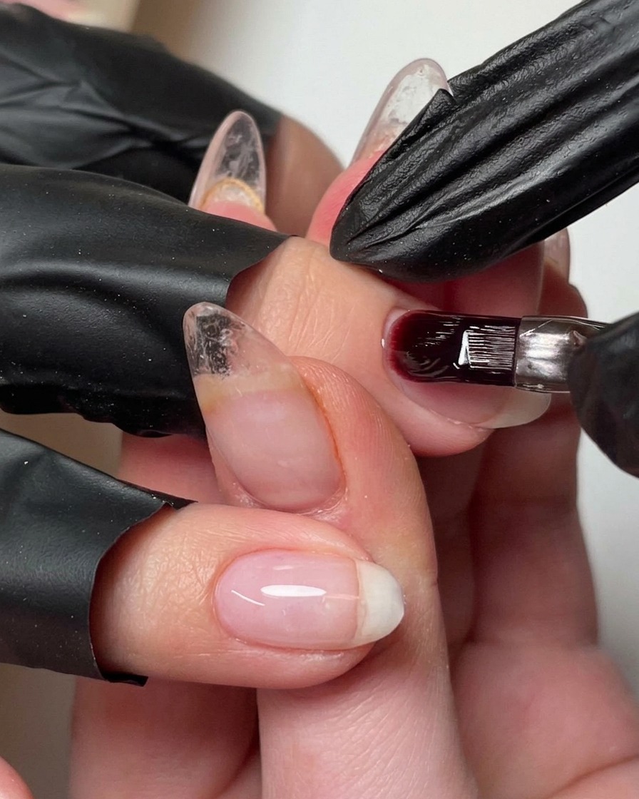 Un pinceau ajoutant une petite goutte de gel de construction sur longle pour affiner le bombé.