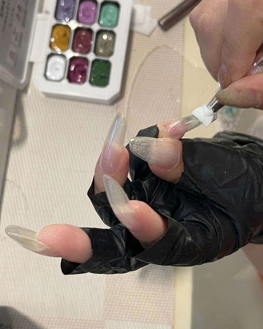 Un gros plan dun pinceau à ongles estompant une douce couleur de gel vert menthe sur la surface dun long ongle structuré pour créer un dégradé délicat.