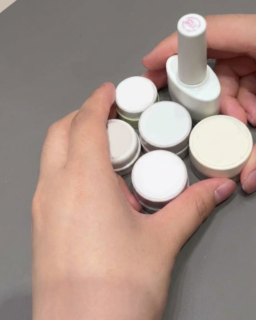 Un pinceau carré utilisé pour lisser et remplir de gel rose une French manucure.