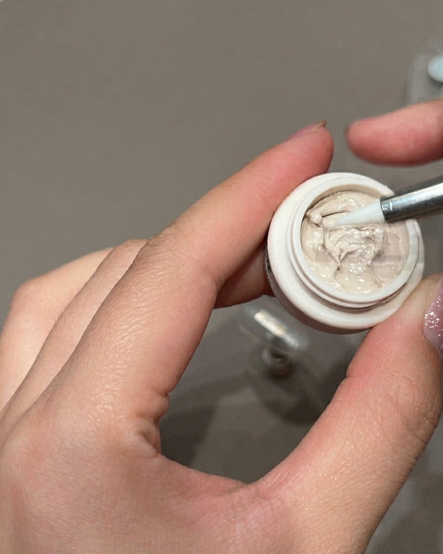 Vue de près dun pinceau liner de précision appliquant de petits pois marron sur un ongle en gel.