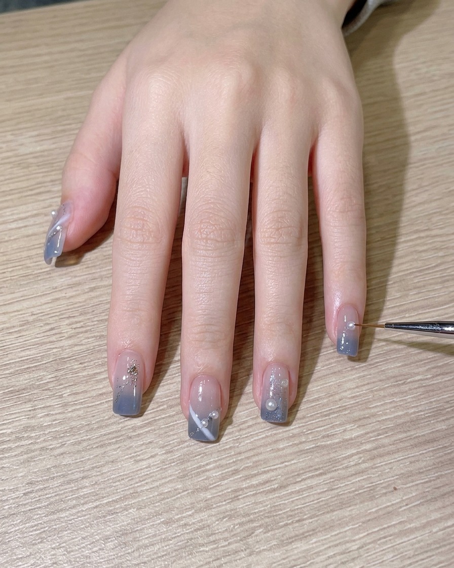 Un pinceau appliquant une dernière couche de top coat brillant sur le nail art terminé.