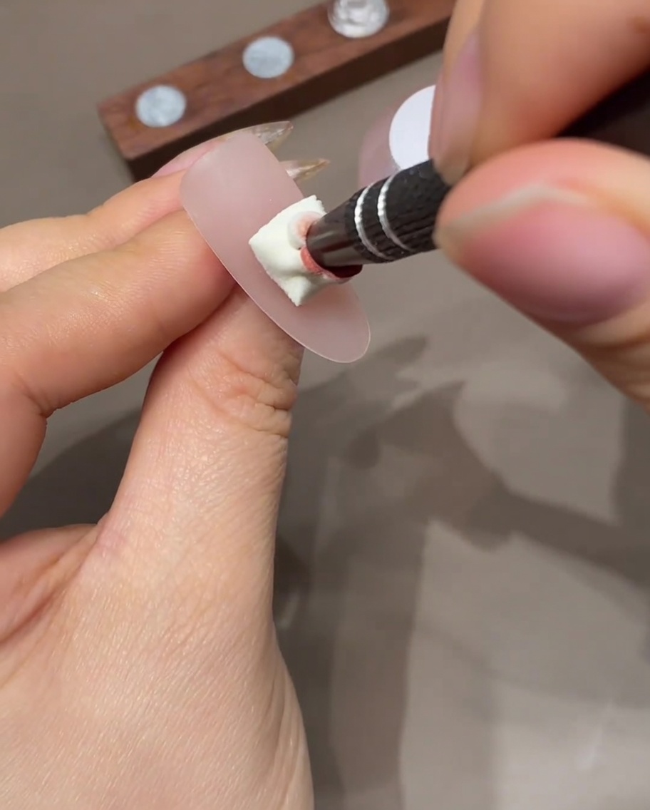 Un ongle avec un effet ombré en cours de catalysation dans une lampe UV professionnelle.