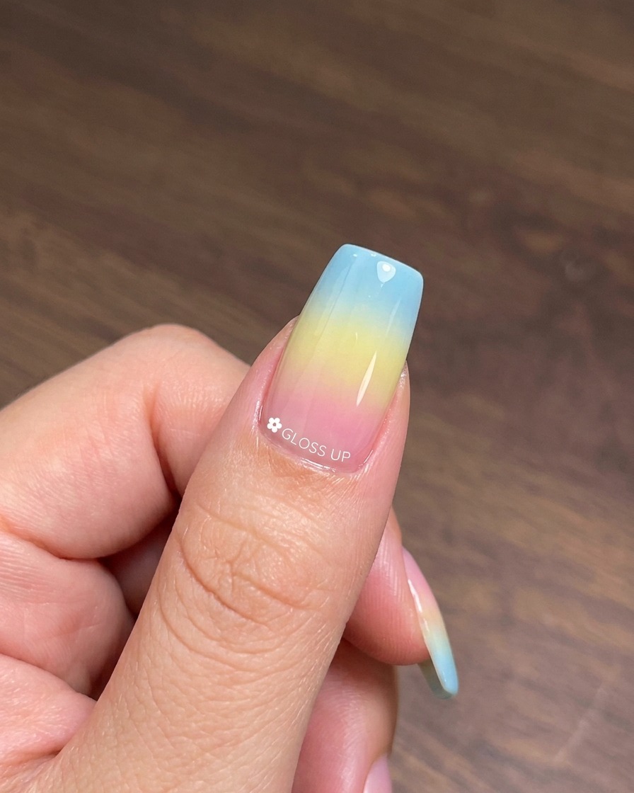 Un pinceau appliquant une couche de vernis gel œil de chat numéro 25 sur la base dégradée multicolore catalysée.