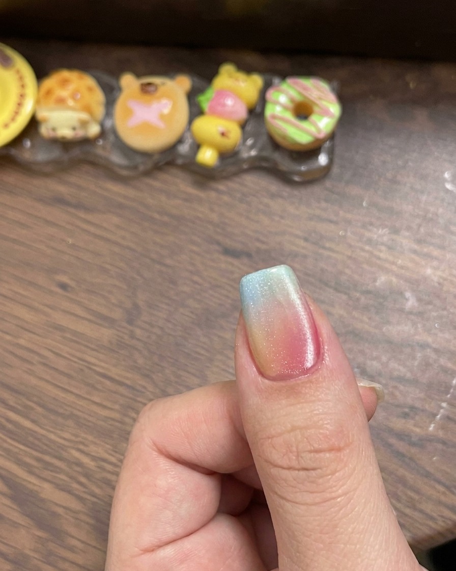 Un outil magnétique tenu près du côté dun ongle recouvert de gel œil de chat humide pour créer un reflet lumineux net.