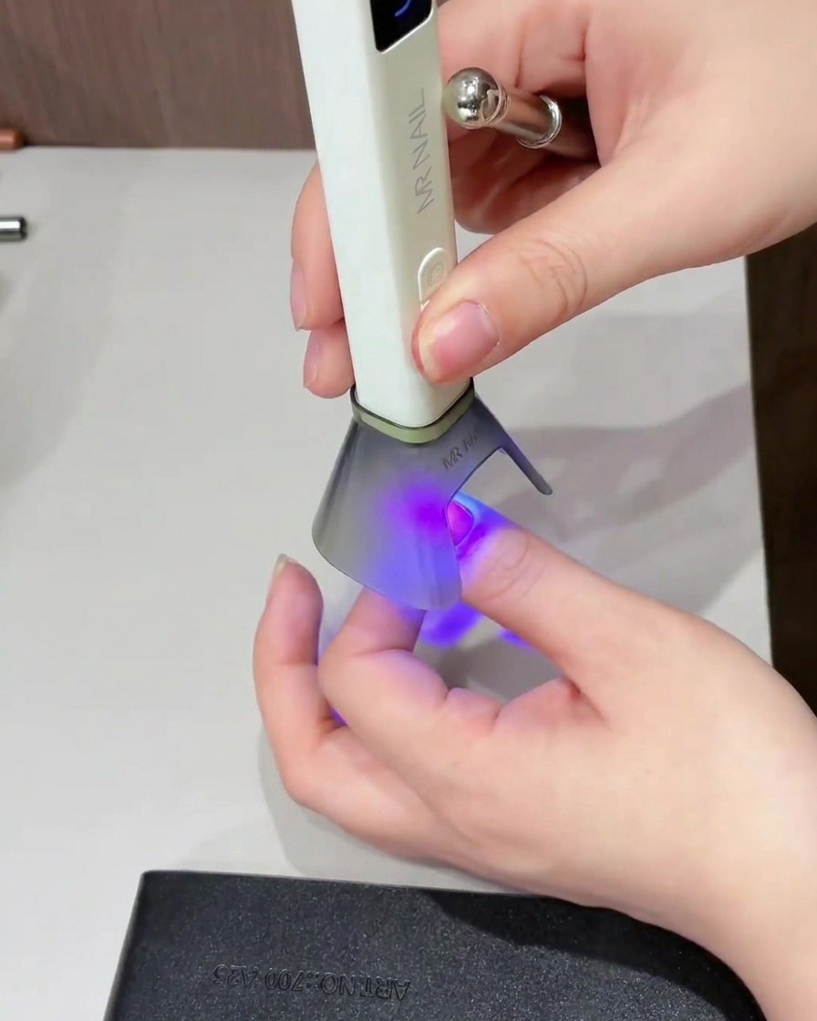 Un pinceau appliquant un top coat brillant sur toute la surface de longle.