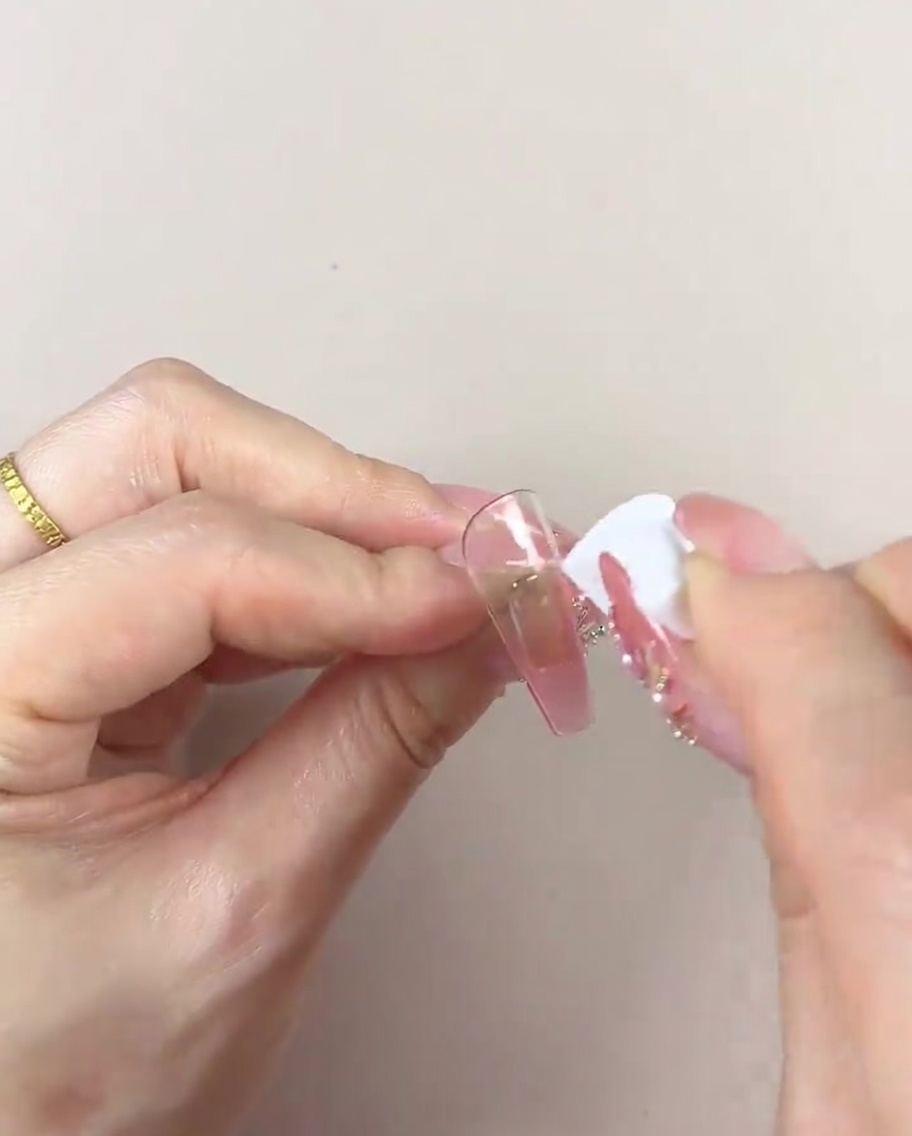 Une main utilisant une section propre dune éponge cosmétique pour lisser et peaufiner le dégradé de couleur sur une pointe dongle.