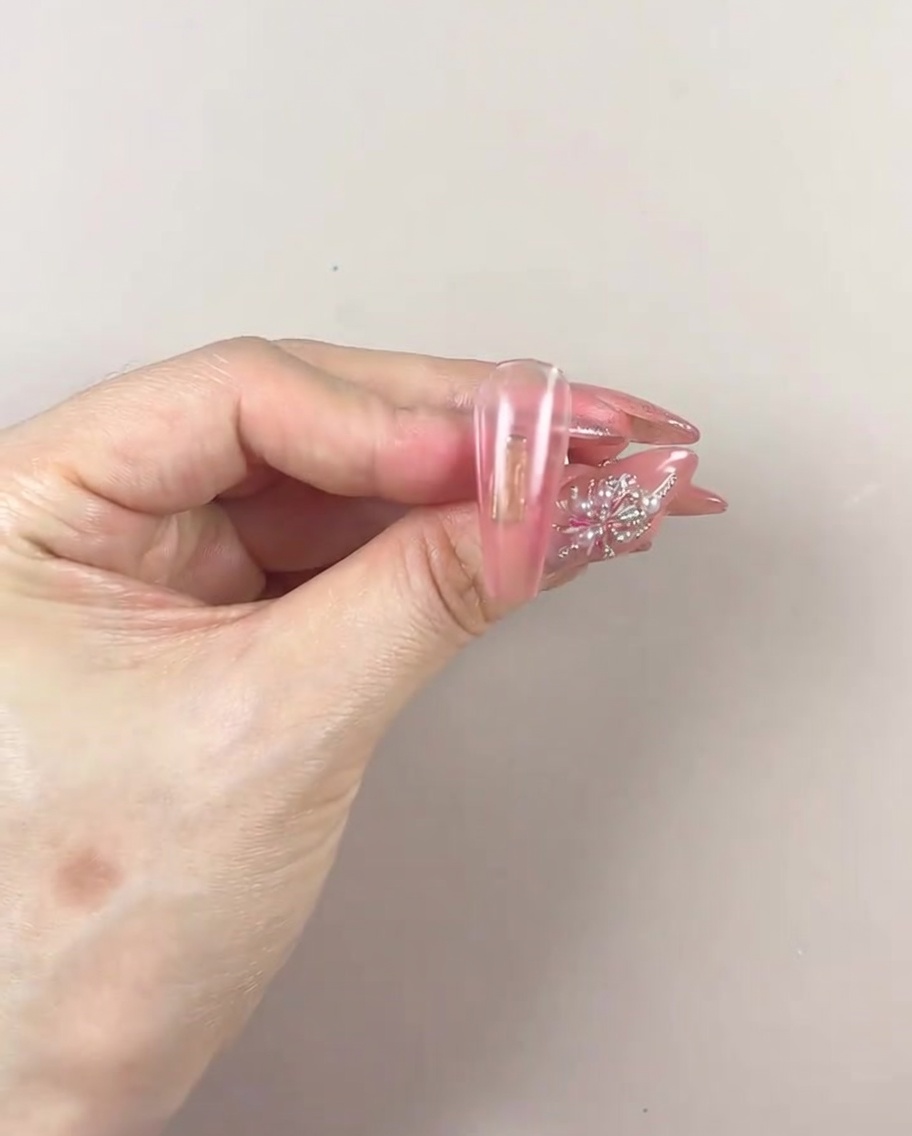 Une main manucurée placée sous une lampe UV/LED pour catalyser la couche de gel dégradée.