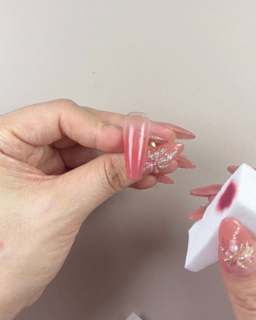 Gros plan dune main utilisant une éponge à maquillage pour tapoter et estomper doucement le dégradé sur un ongle.