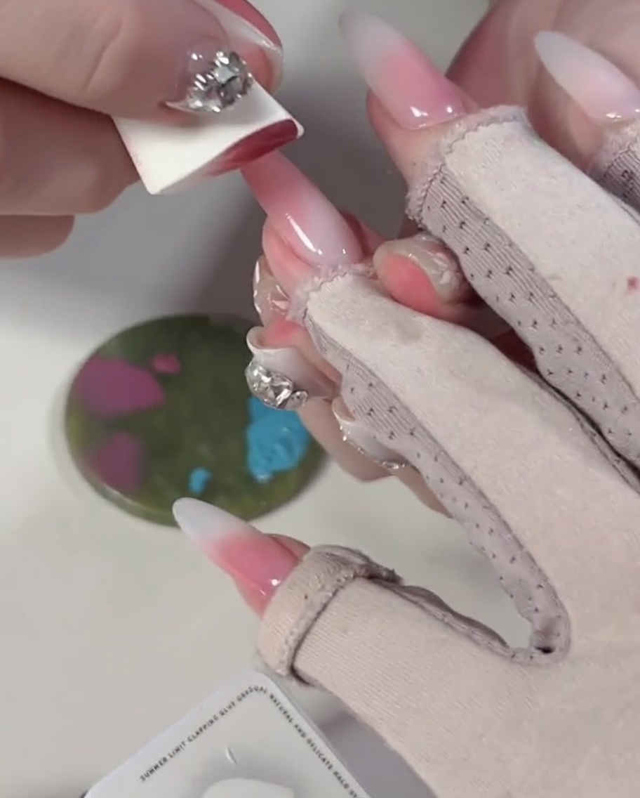 Gros plan dune éponge pressée sur des blocs de vernis gel bleu et rose sur une palette de mélange.