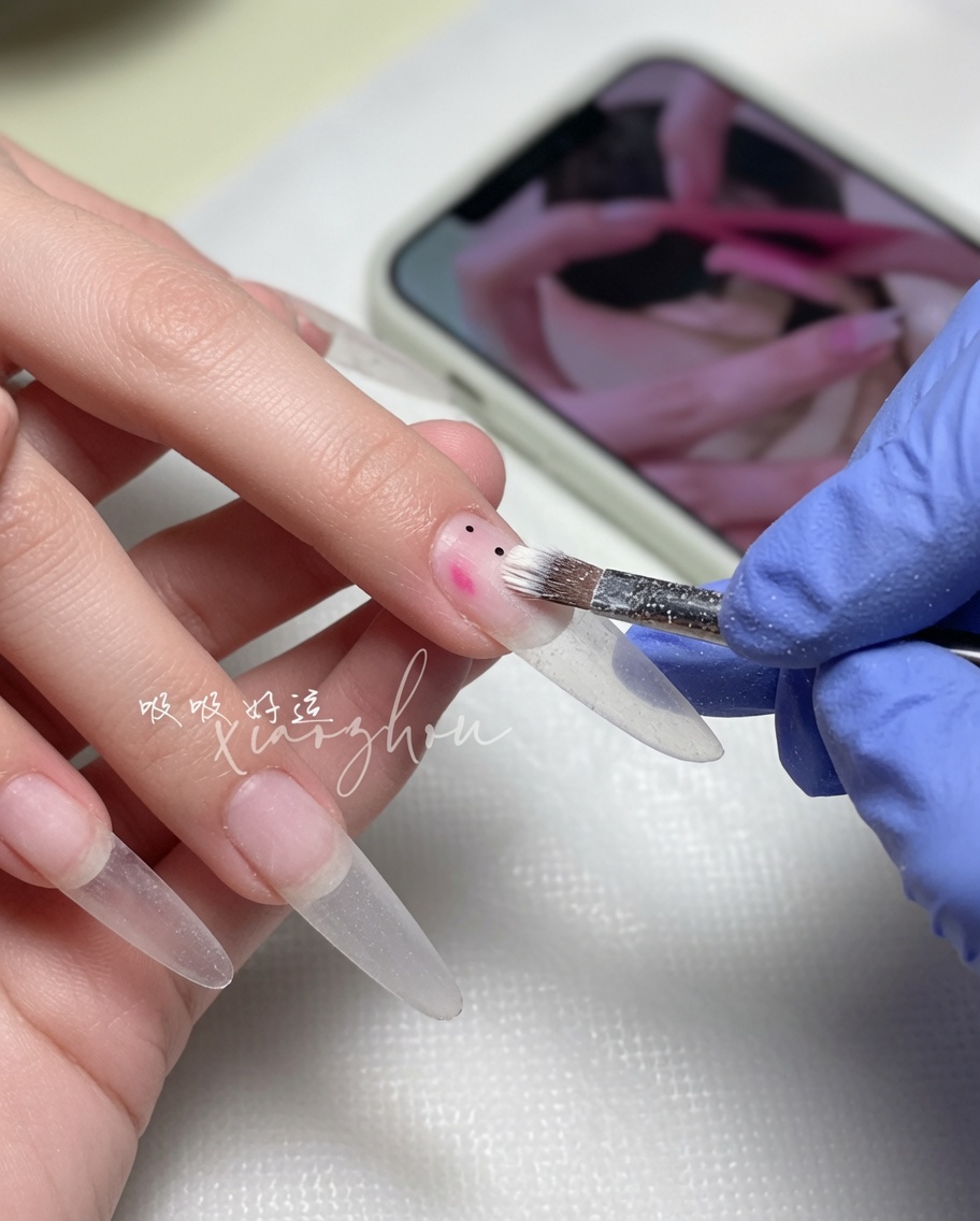 Un pinceau à ongles répartissant un vernis gel nude doux sur la plaque de longle.