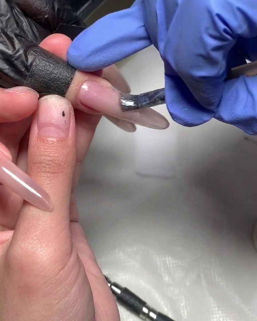 Un pinceau appliquant une nouvelle couche de gel magenta sur lextrémité de longle pour augmenter lintensité.