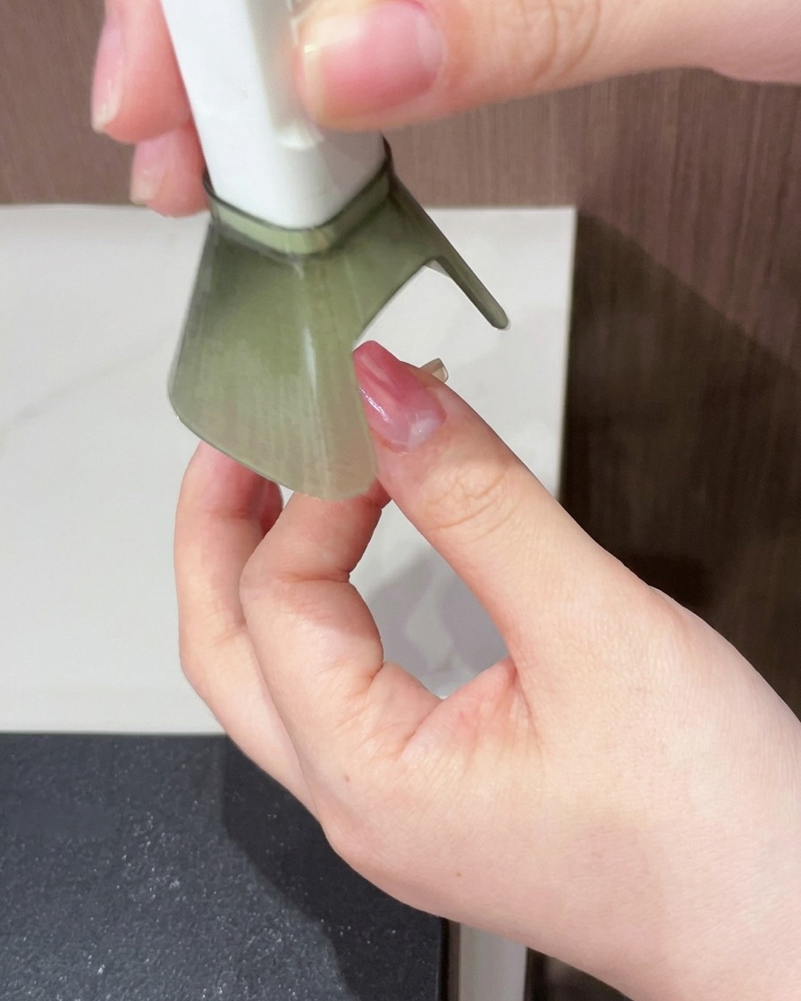 Un ongle avec une base dégradée magenta en train de catalyser sous une lampe UV/LED portable.