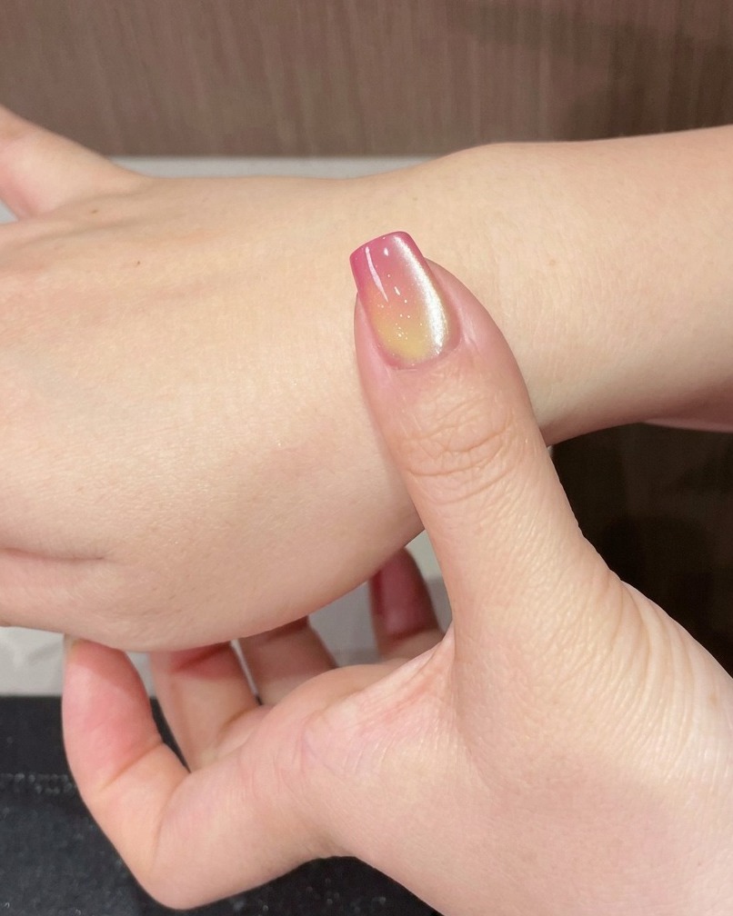 Un doigt avec un ongle cat-eye placé sous une lampe UV portable.