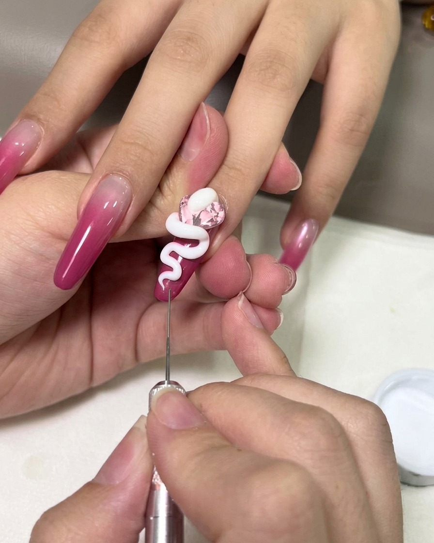 Gros plan dune main utilisant un outil de précision pour sculpter le serpent en gel blanc sur le cristal.