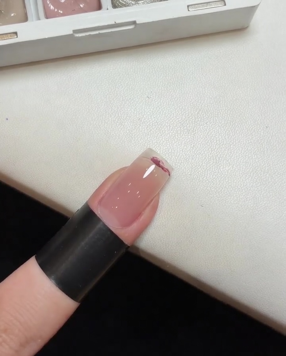 Un outil éponge utilisé pour tapoter et estomper le vernis gel rose sur un ongle afin de former un effet de dégradécite: 1.