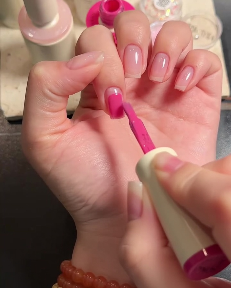 Gros plan dun pinceau plat appliquant du gel rose sur la surface dun ongle.