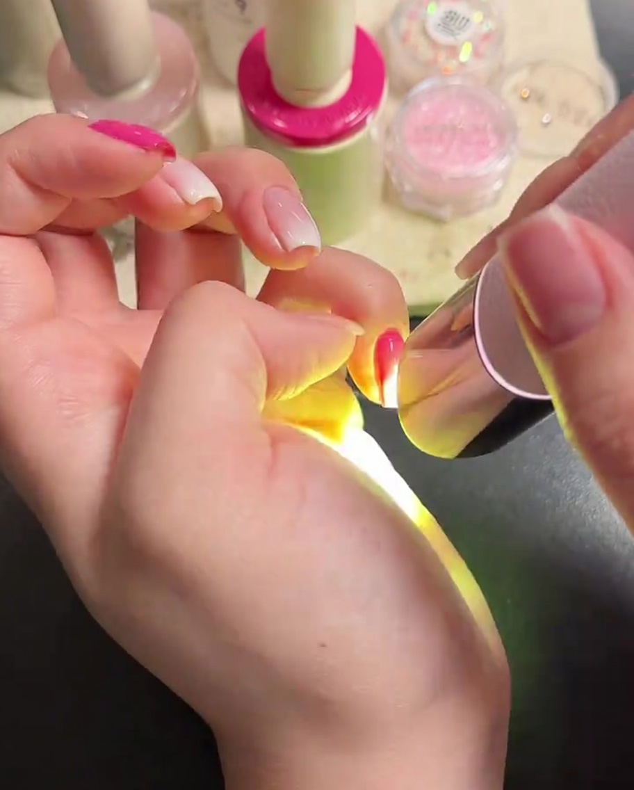 Un pinceau à ongles appliquant une couche de finition transparente et brillante.
