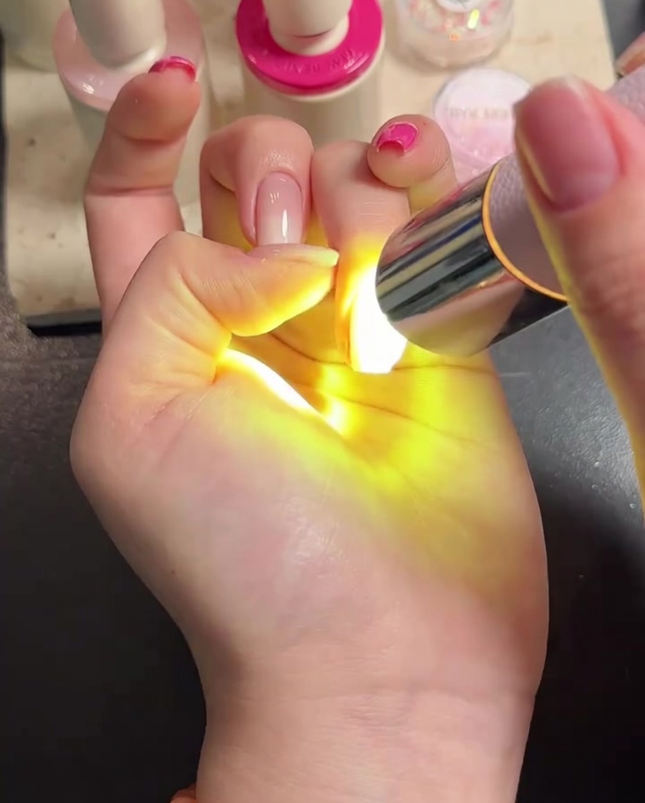 Une main placée sous une lampe LED, les doigts bien visibles pendant la catalysation.